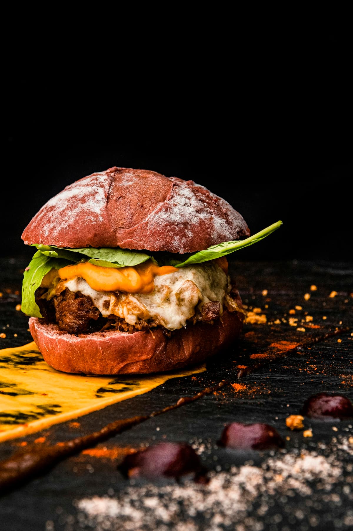 Hamburguesa con queso fundido y hojas verdes en pan artesanal sobre pizarra negra